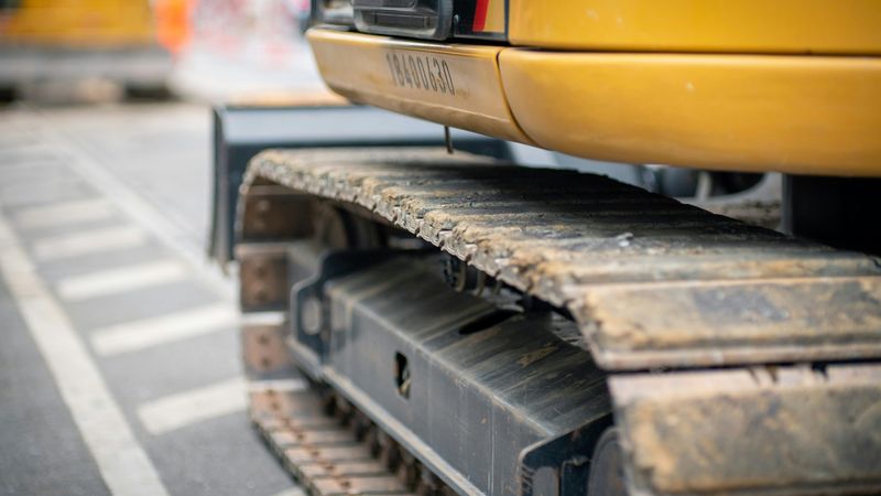 Ein gelber Bagger auf einer Baustelle, der auf einem Kettenfahrzeug steht.