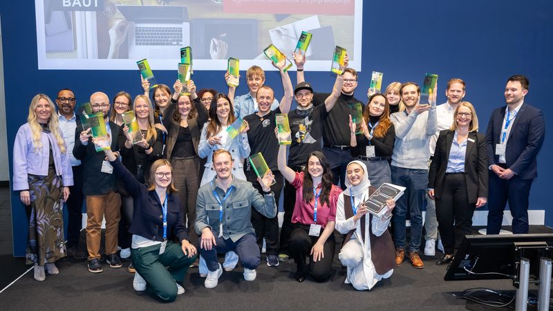 Eine Gruppe von Menschen hält stolz ihre Auszeichnungen in die Höhe.