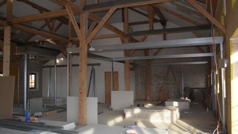 Ein Innenraum während der Renovierung mit sichtbaren Holzbalken und Baumaterialien.