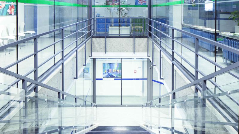 Ein modernes Treppenhaus mit Glaswänden und Metallgeländern in einem Bürogebäude.