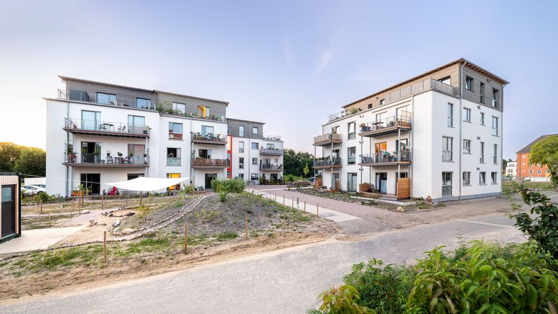 Ein modernes Wohngebäude mit mehreren Etagen und Balkonen in einer ruhigen Wohngegend.