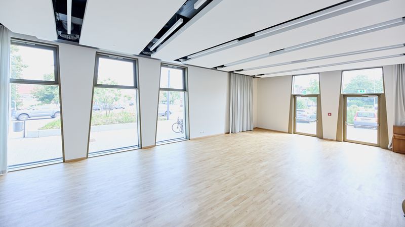 Ein moderner Raum mit großen Fenstern und hellem Holzboden.