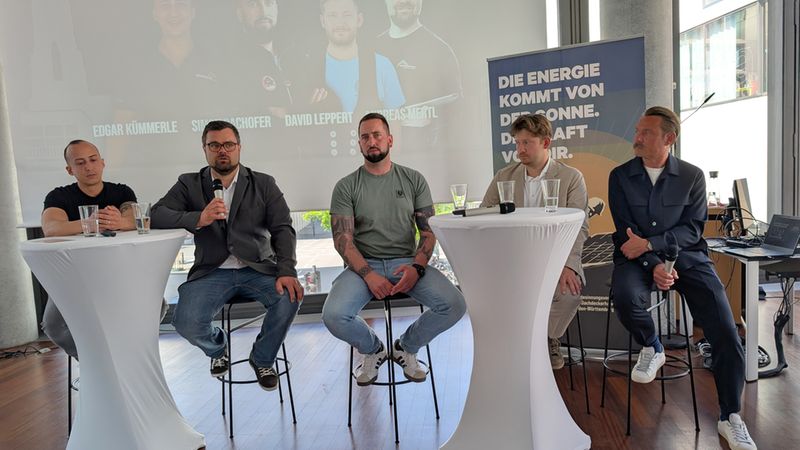 Eine Gruppe von fünf Männern sitzt auf einer Bühne bei einer Paneldiskussion über Digitalisierung.