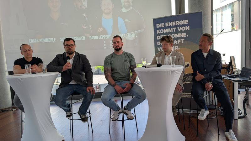 Eine Gruppe von fünf Männern sitzt auf einer Bühne bei einer Paneldiskussion über Digitalisierung.