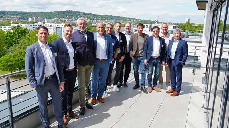 Eine Gruppe von Geschäftsleuten steht auf einer Dachterrasse mit Blick auf die Stadt im Hintergrund.