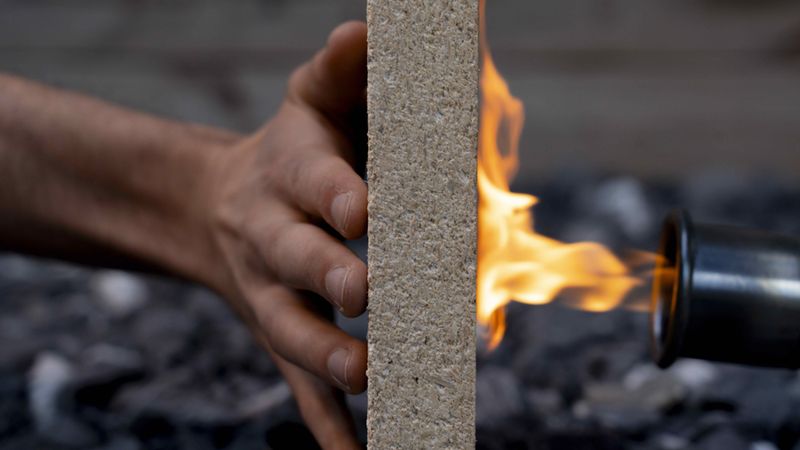 Eine feuerfeste Platte wird mit einer Flamme getestet, während eine Hand die Platte hält.