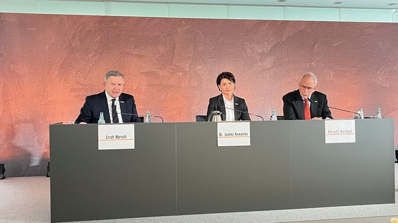Ein Panel von drei Personen bei einer Pressekonferenz, die an einem Tisch sitzen.