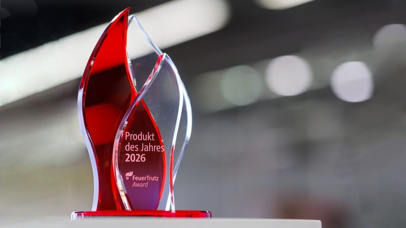 Eine elegante Trophäe mit der Aufschrift "Produkt des Jahres 2026" und "FeuerTrutz Award" auf einem unscharfen Hintergrund.
