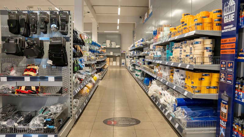 Ein leerer Gang in einem Baumarkt mit Regalen voller Werkzeuge und Baumaterialien.