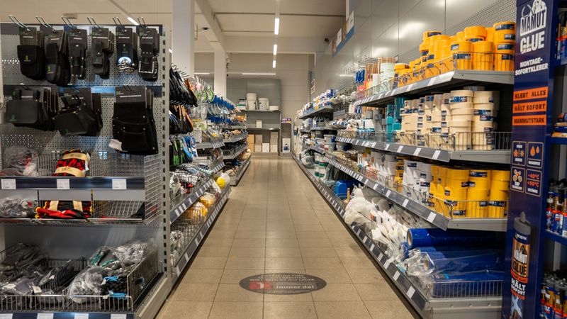 Ein leerer Gang in einem Baumarkt mit Regalen voller Werkzeuge und Baumaterialien.