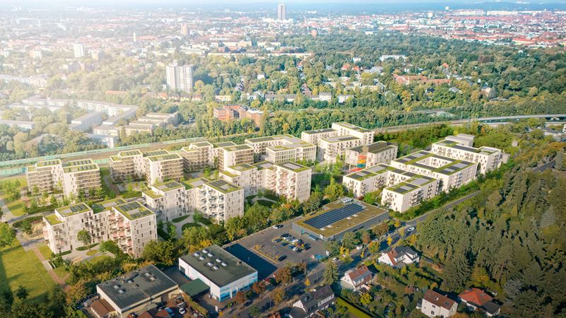Luftaufnahme einer modernen Wohnanlage inmitten einer grünen Stadtlandschaft.