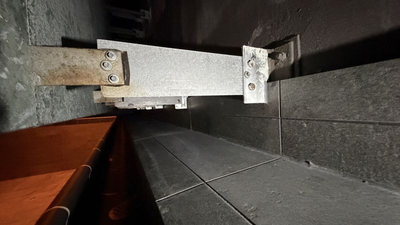 Ein massiver Metallträger in einer dunklen Industrieumgebung, befestigt an einer Wand.