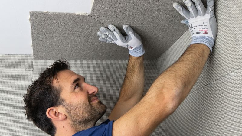 Ein Handwerker installiert eine Keilplatte an einer Decke in einem Innenraum