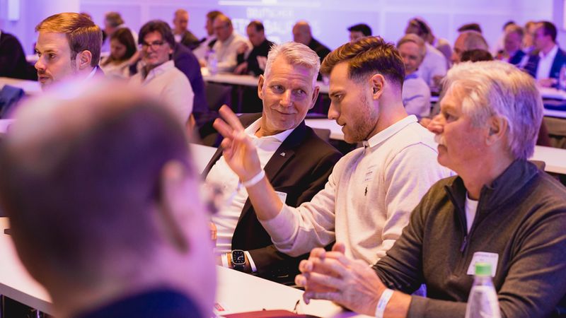 Teilnehmer einer Konferenz diskutieren angeregt in einem modernen Konferenzraum.