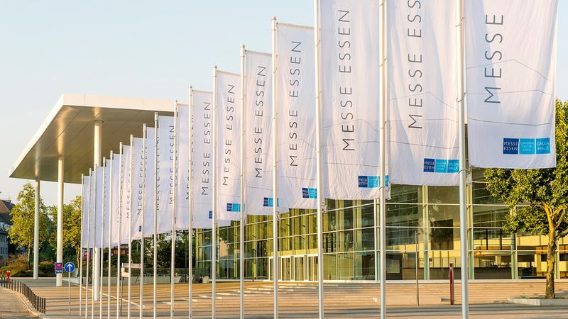 Außenansicht der Messe Essen mit wehenden Fahnen im Vordergrund.