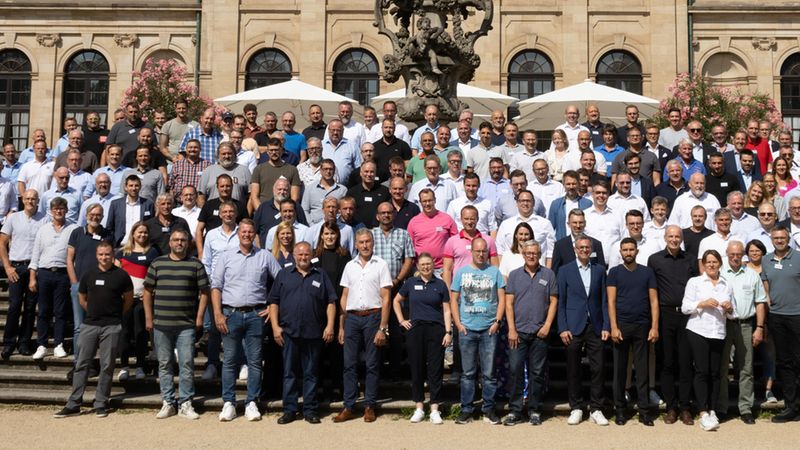 Ein großes Gruppenfoto von Menschen, die vor einem historischen Gebäude auf einer Treppe stehen.