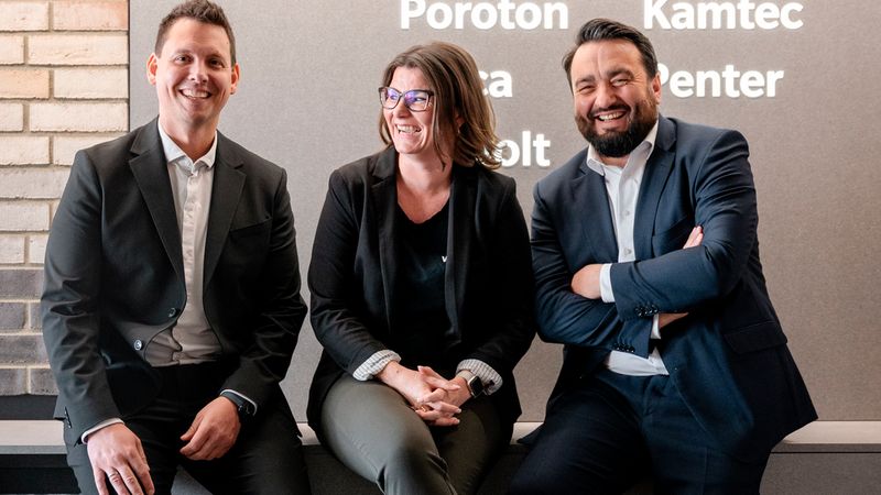 Ein Gruppenfoto von drei Personen, die vor einem Wienerberger-Logo sitzen.