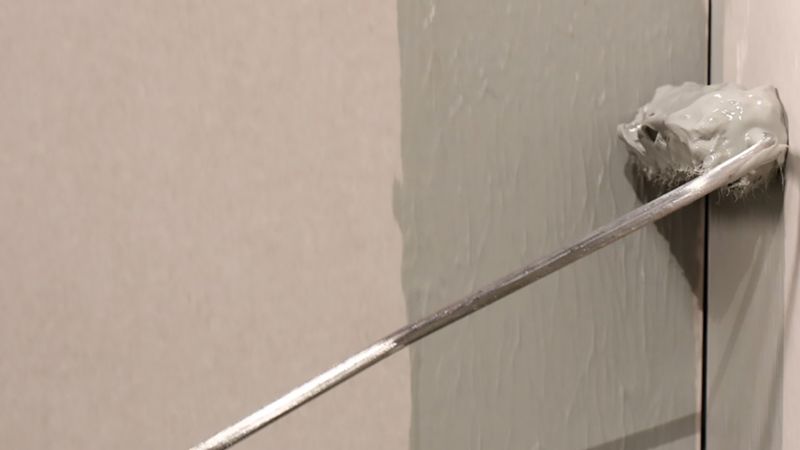 Eine Rolle an einer Wand, die Abdichtung aufbringt