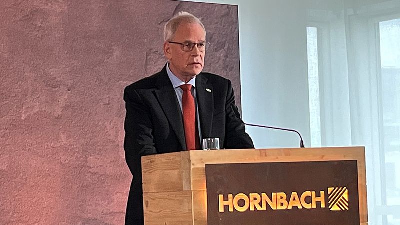 Ein Mann steht an einem Rednerpult mit dem Logo von Hornbach.