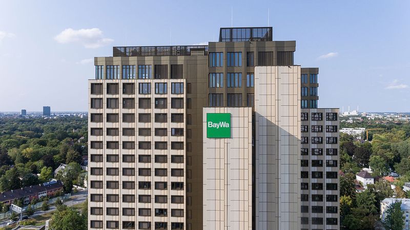 Das Bild zeigt das BayWa Hochhaus in München, umgeben von einer grünen Landschaft und städtischer Umgebung.