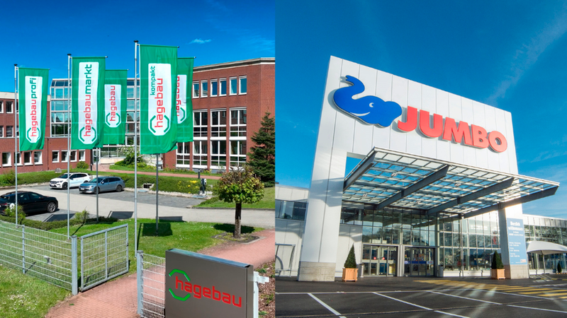 Hauptmotiv: Außenansichten zweier Einzelhandelsfilialen – links die Hagebau-Filiale mit grünen Fahnen, Firmenlogo und Backsteinfassade, rechts die Jumbo-Filiale mit großem Elefanten-Logo über dem gläsernen Eingangsbereich; blauer Himmel, Parkplatz und Eingangsbereiche sichtbar.
