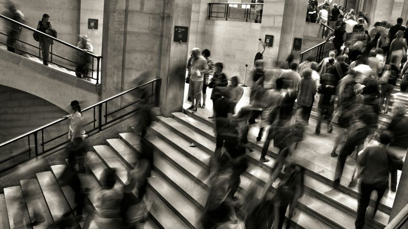 Eine große Menschenmenge bewegt sich auf einer Treppe in einem öffentlichen Gebäude.