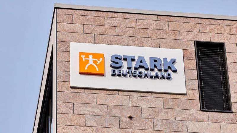 Ein detaillierter Blick auf das markante Firmenlogo von Stark Deutschland, das an der modern gestalteten Steinfassade eines Bürogebäudes angebracht ist.