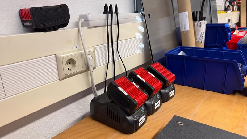 Eine Ladestation mit mehreren Akkus auf einer Werkbank in einer Werkstatt.