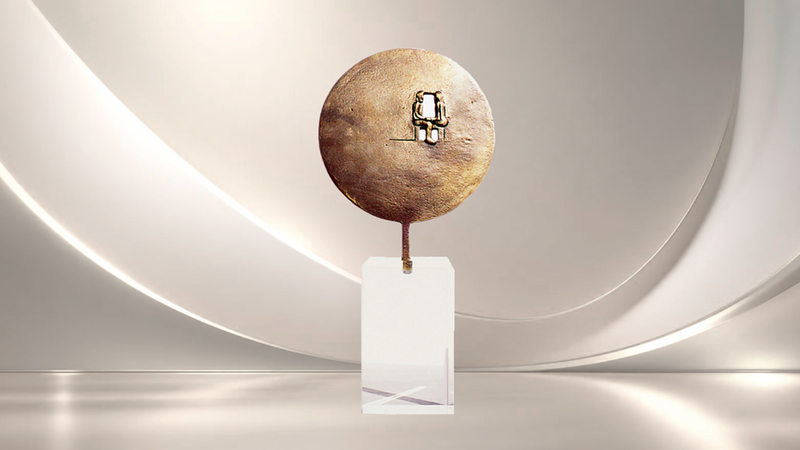 Eine abstrakte, runde Bronzeskulptur mit einer kleinen Durchbruch-Öffnung, die auf einem transparenten Acrylsockel vor einem minimalistischen, hellen Hintergrund präsentiert wird.