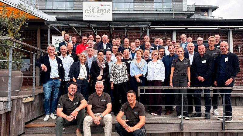 Ein weitläufiges Gruppenfoto von den Teilnehmer:innen der Mitgliederversammlung der RAL Gütegemeinschaft Trockenbau e.V. 2026 die vor der Eventlocation esCape für ein gemeinsames Bild posieren.