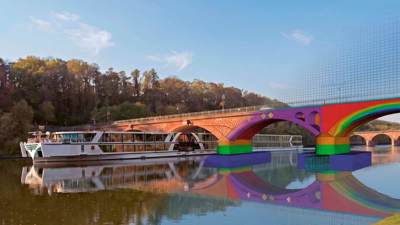Ein Schiff fährt unter einer Steinbogenbrücke hindurch.