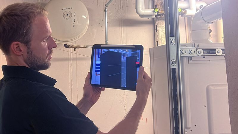 Ein Mann nutzt ein Tablet mit der "Heat Pump PlanAR"-App.