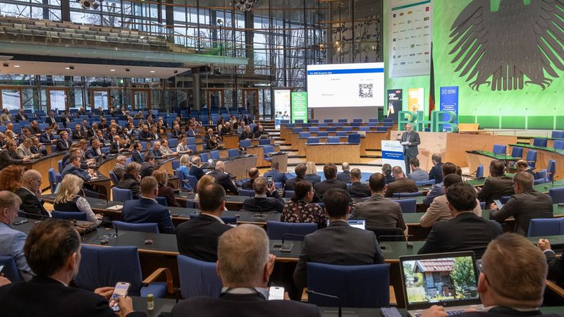 Ein großer Konferenzsaal mit vielen Teilnehmern, die einem Vortrag lauschen.