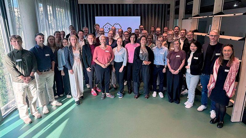 Eine große Gruppe von Mitarbeitern oder Teilnehmern einer Veranstaltung posiert lächelnd für ein Gruppenfoto.