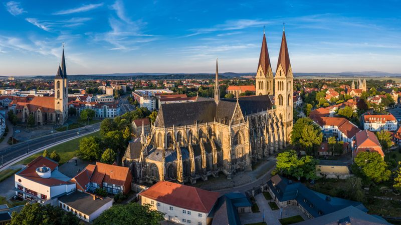Ein Luftbild-Blick auf den Dom zu Halberstadt in Deutschland, umgeben von der historischen Stadtlandschaft und einem strahlend blauen Himmel.