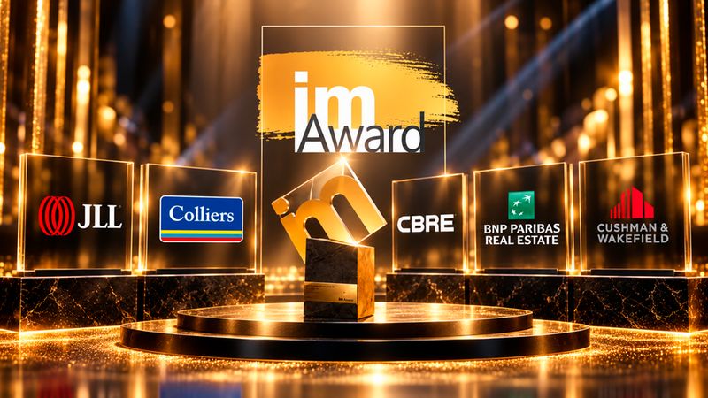 Eine glanzvolle Inszenierung des imAward auf einem Podest, umgeben von prominenten Logos führender Immobilienunternehmen wie JLL, Colliers, CBRE, BNP Paribas Real Estate und Cushman & Wakefield in einem luxuriösen, golden beleuchteten Ambiente.