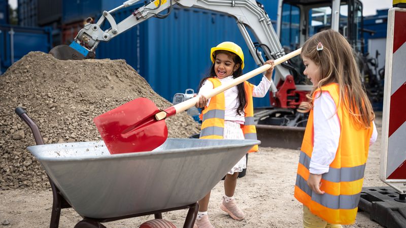 Zwei kleine Mädchen spielen auf einer Baustelle.