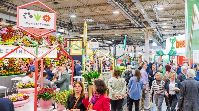 Eine belebte Ausstellungshalle auf einer Blumenmesse mit zahlreichen Besuchern und bunten Blumenständen.