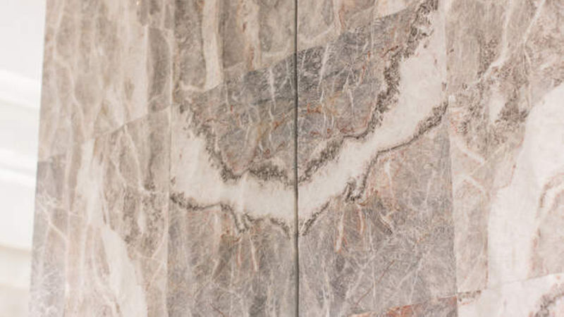 Die Wand hinter der Theke ist ebenfalls mit „Fior di Pesco Carnico“ in spiegelbildlicher Verlegung und 3D-Oberflächenverarbeitung „Onda“ (Italienisch für „Welle“) verkleidet. 