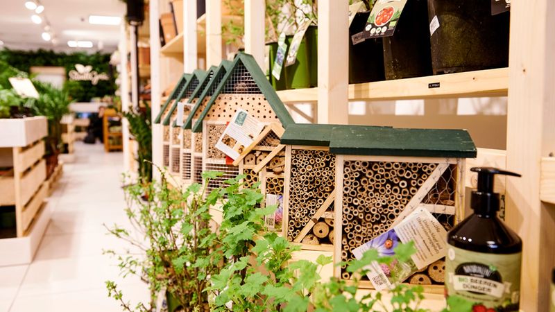 Ein Insektenhotel in einem Gartencenter, umgeben von Pflanzen und Gartenprodukten.