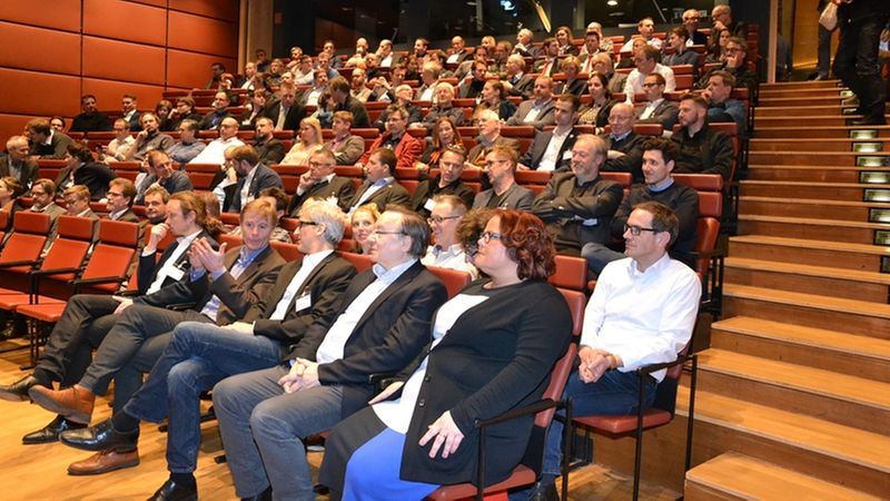 Ein voll besetzter Konferenzsaal mit aufmerksamem Publikum.