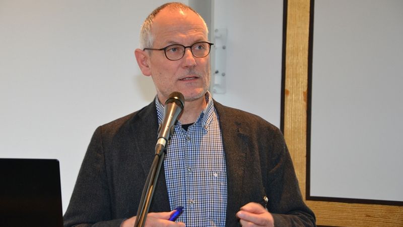 Ein Mann hält eine Rede am Rednerpult und spricht in ein Mikrofon.