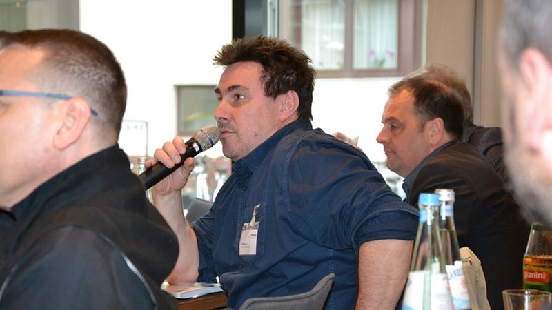 Ein Mann spricht in ein Mikrofon während einer Konferenz.