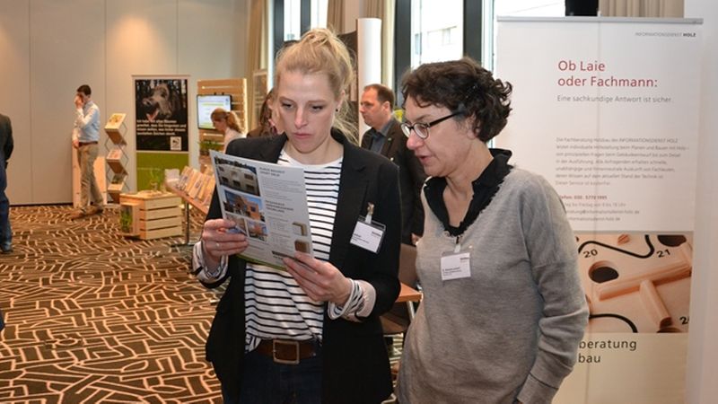 Zwei Frauen betrachten eine Broschüre auf einer Fachmesse.