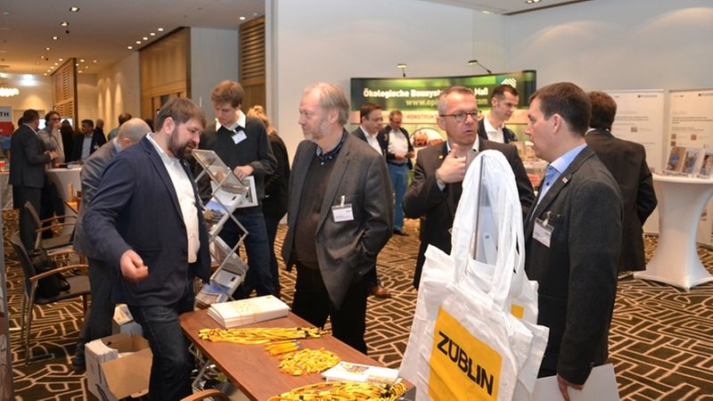 Teilnehmer eines Netzwerktreffens auf einer Messe, die sich an einem Stand unterhalten.