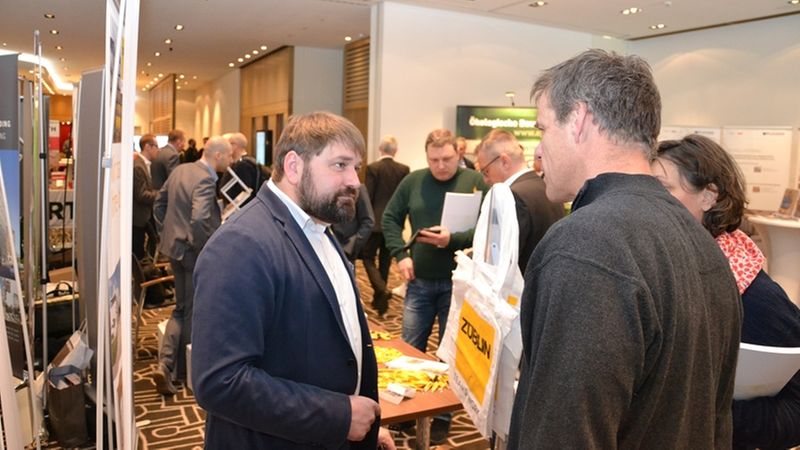 Ein geschäftliches Treffen auf einer Messe mit mehreren Personen, die sich unterhalten.