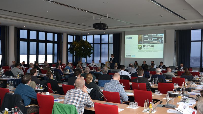 Teilnehmer sitzen in einem Konferenzraum beim 15. Holzbau Forum 2016, während ein Vortrag gehalten wird.