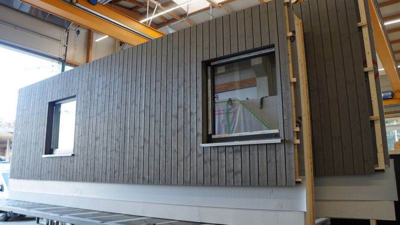 Bereits im Werk wurden die Holztafelelemente für die Fassade mit Fenstern, Dämmung, Lattung und Installation versehen, um eine schnelle Montage auf der Baustelle zu gewährleisten. Foto: Brünninghoff