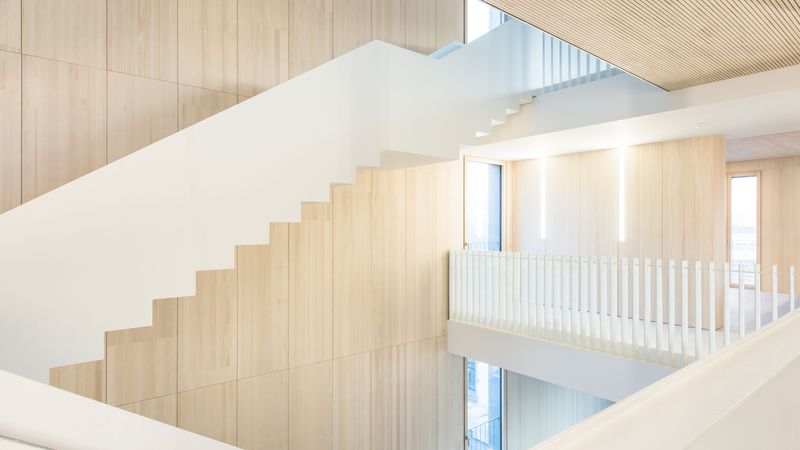 Die filigranen, frei tragenden Stahltreppenläufe wurden hier millimetergenau zwischen die Deckenkonstruktionen eingehängt. Die über drei Geschosse durchlaufende Außenwand mit geschlossener Echtholz-Oberfläche bleibt dabei durchgehend sichtbar. Foto: Lignotrend / Foto: Olaf Herzog, Waldkirch