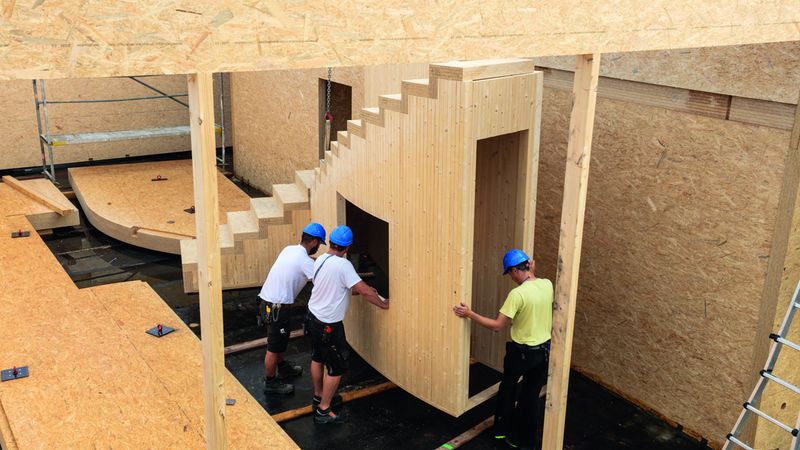 Vorgefertigtes Treppenelement wird mit dem Kran an die richtige Stelle positioniert und fachmännisch montiert. Foto: Swiss Krono Tex GmbH & Co. KG / Foto: tm studios